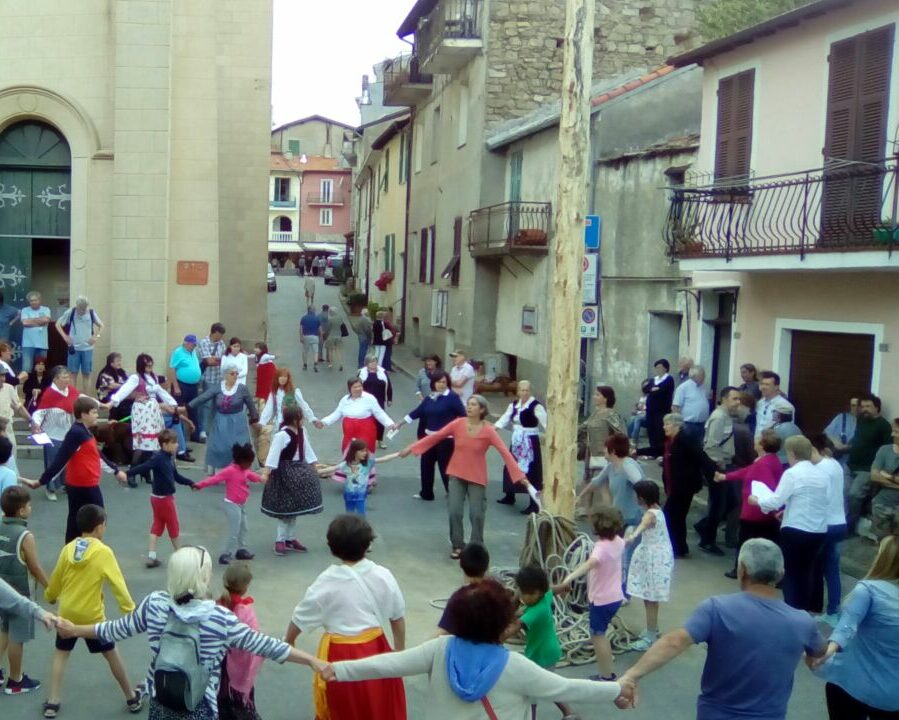 Dei bambini in cerchio ballano intorno a un legno per la festa del Ra Barca